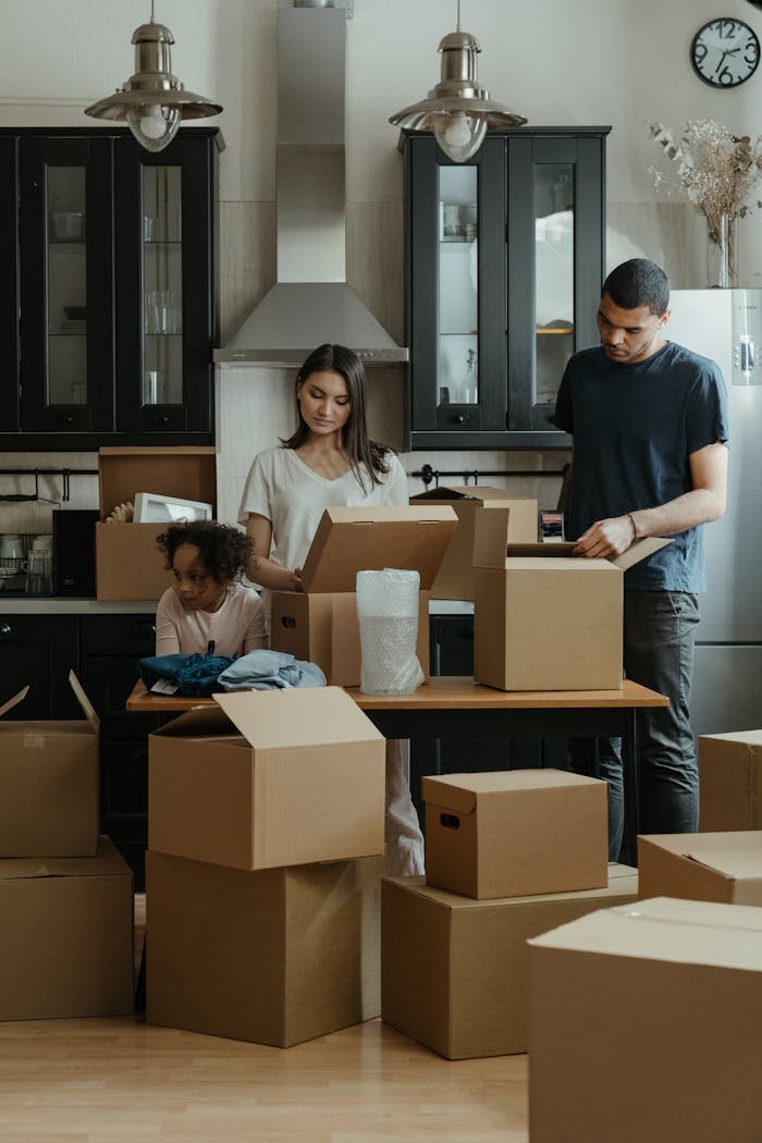 services-02 Family unpacking boxes together in a modern kitchen after moving into a new home.